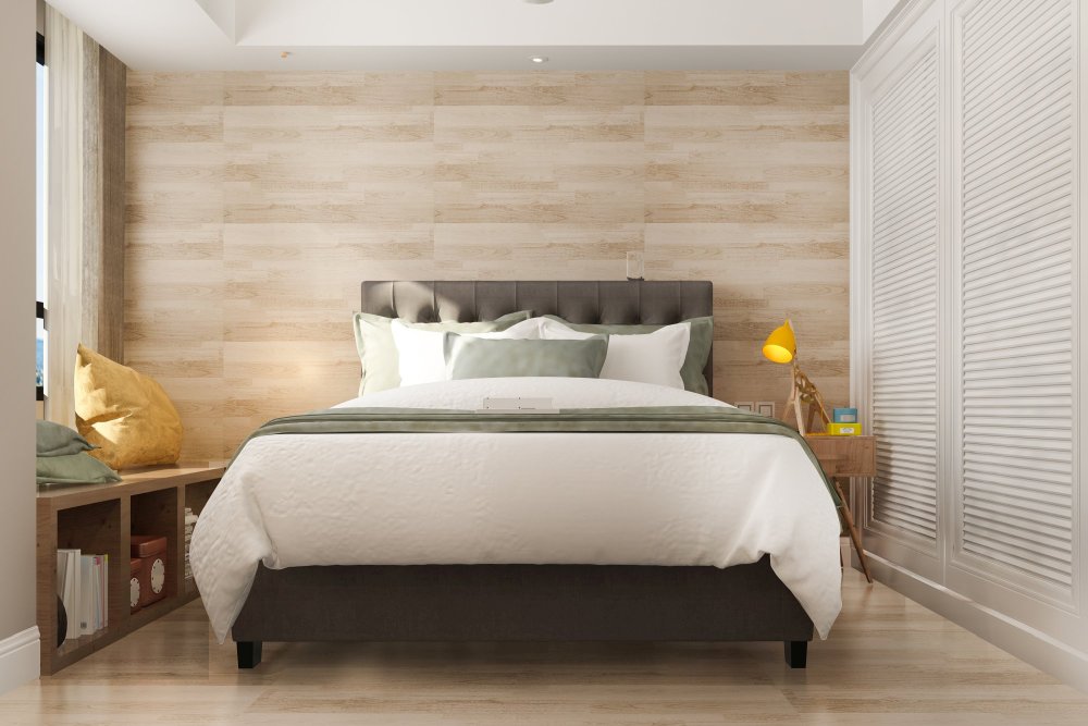 Mała przytulna sypialnia z tapicerowanym łóżkiem i żółtą lampką na stoliku